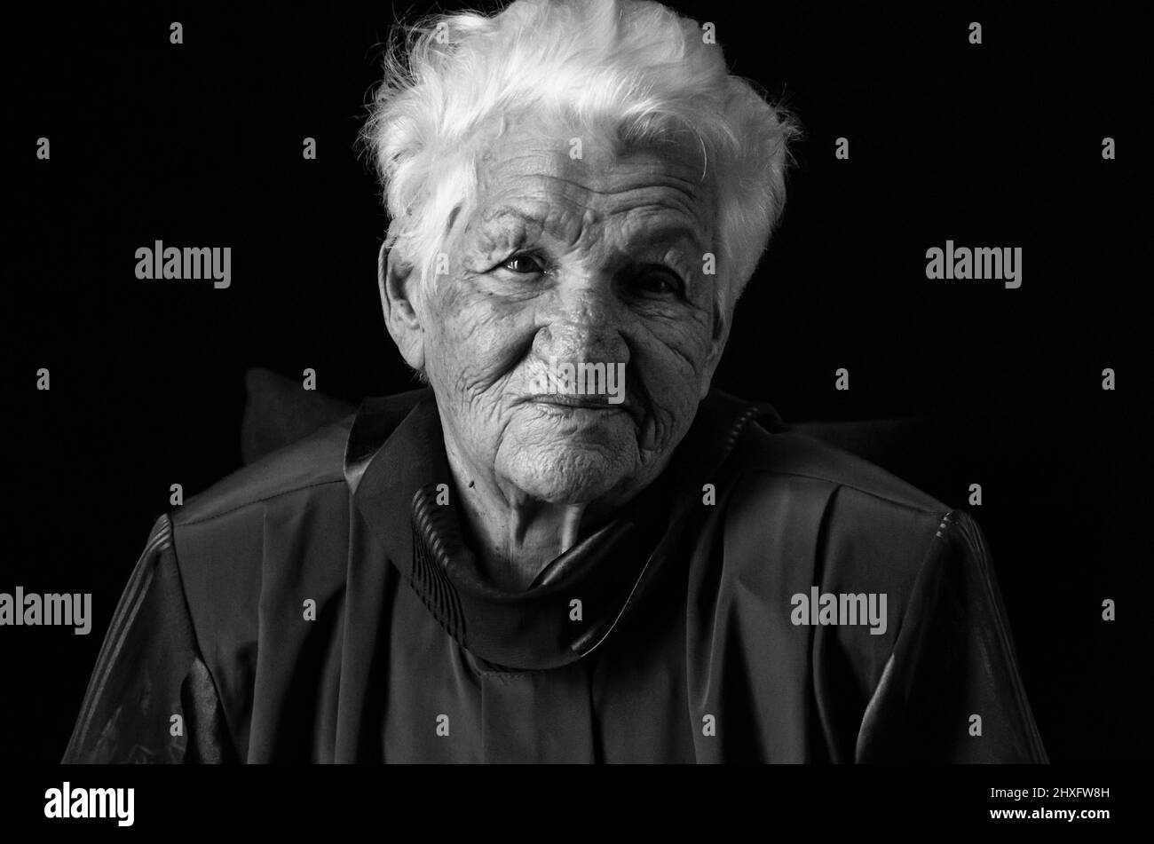 Portrait d'une femme âgée sérieuse sur fond noir. Photo en noir et blanc. Banque D'Images