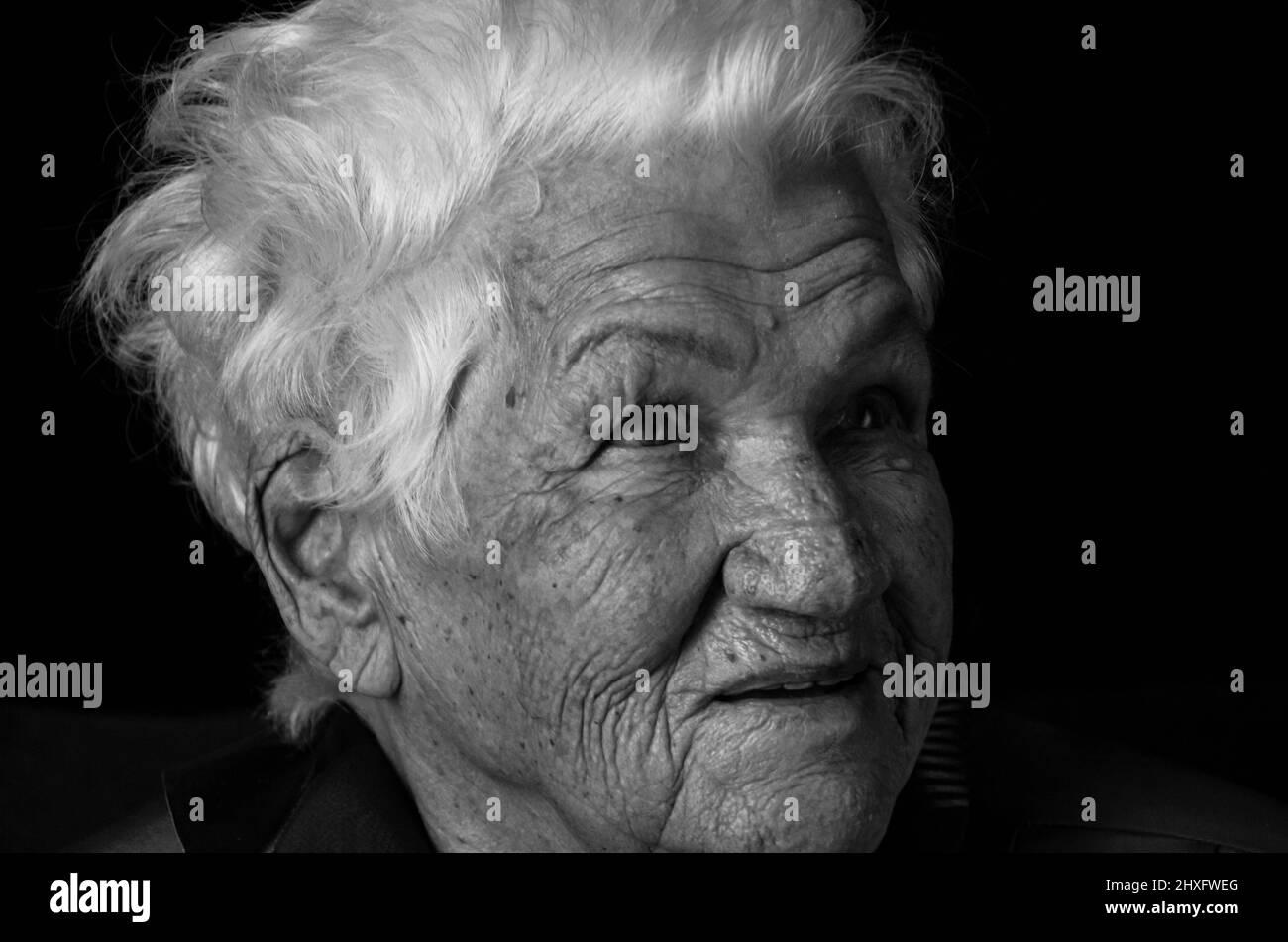 Portrait d'une femme âgée sérieuse sur fond noir. Photo en noir et blanc. Banque D'Images