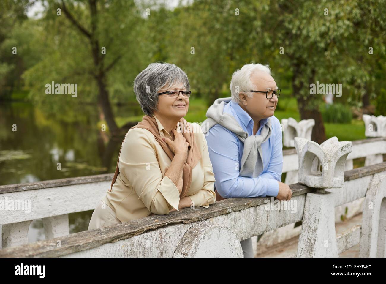 Heureux vieux couple senior debout sur le pont profiter du beau temps et du paysage du parc Banque D'Images