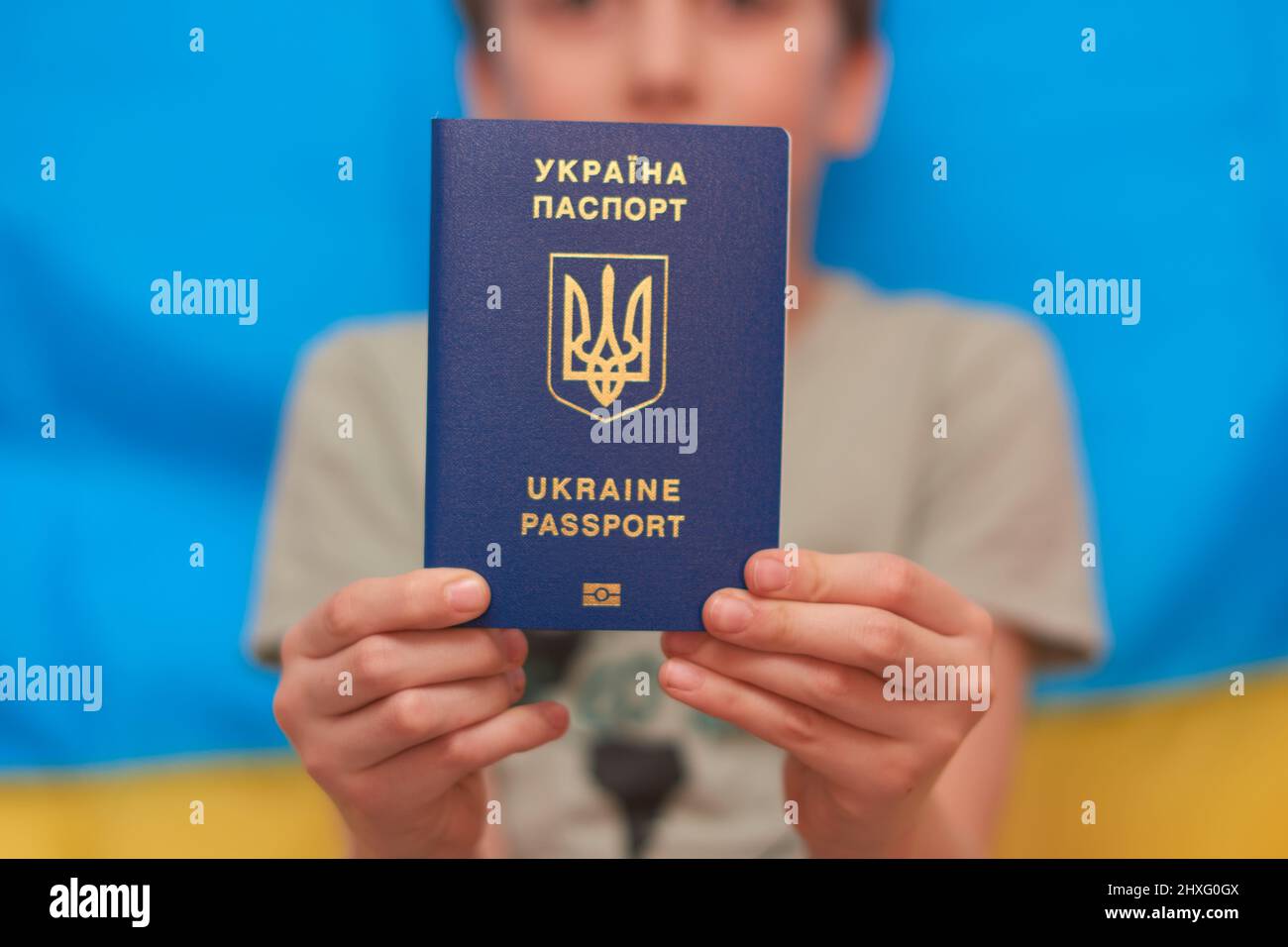 Garçon tenant entre les mains passeport ukrainien sur fond jaune-bleu. Les enfants soutiennent l'Ukraine en montrant leur cœur sur un drapeau jaune-bleu. Crise ukrainienne, agression russe en Ukraine. Guerre de la Russie contre l'Ukraine. Banque D'Images