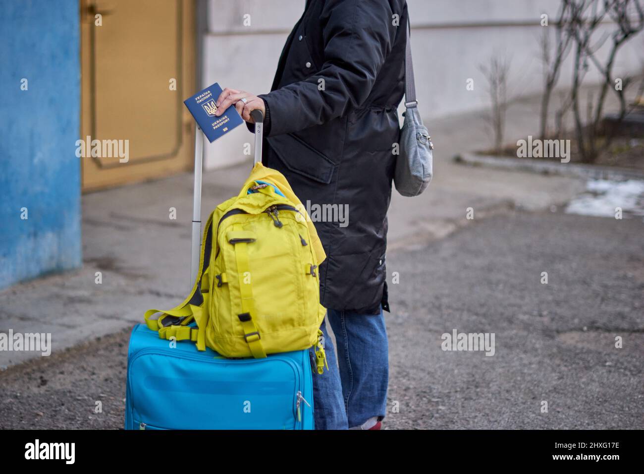 Évacuation des civils, triste enfant avec le drapeau de l'Ukraine. Famille de réfugiés d'Ukraine traversant la frontière. Main tenant un passeport au-dessus des bagages avec drapeau jaune-bleu. Cessez la guerre, soutenez l'Ukraine Banque D'Images