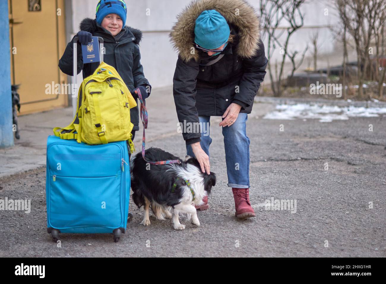 Évacuation des civils, triste enfant avec le drapeau de l'Ukraine. Famille de réfugiés d'Ukraine traversant la frontière. Main tenant un passeport au-dessus des bagages avec drapeau jaune-bleu. Cessez la guerre, soutenez l'Ukraine Banque D'Images