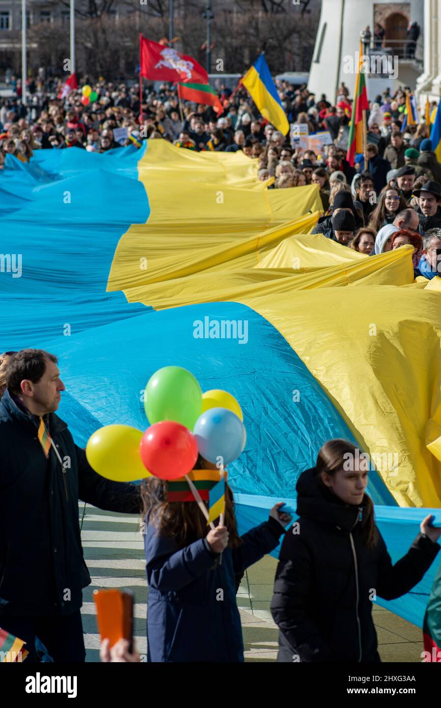 Immense drapeau ukrainien sur la place de la cathédrale de Vilnius, porté par des personnes agitant le drapeau lituanien, ukrainien et biélorusse lors d'une manifestation contre la guerre Banque D'Images