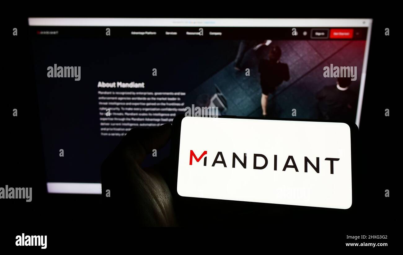 Personne tenant un téléphone mobile avec le logo de la société américaine de cybersécurité Mandiant Inc. À l'écran devant la page Web. Mise au point sur l'affichage du téléphone. Banque D'Images