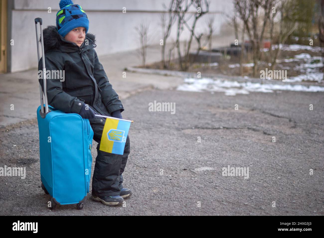 Évacuation des civils, triste enfant avec le drapeau de l'Ukraine. Famille de réfugiés d'Ukraine traversant la frontière. Main tenant un passeport au-dessus des bagages avec drapeau jaune-bleu. Cessez la guerre, soutenez l'Ukraine Banque D'Images