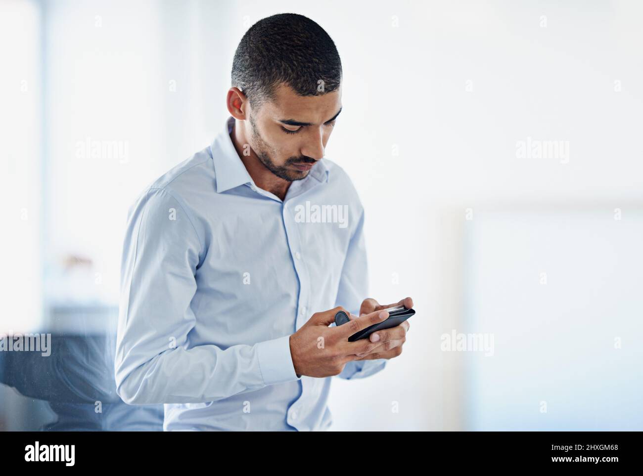 Garder ses contacts à jour. Photo d'un jeune homme d'affaires envoyant un message texte dans un bureau. Banque D'Images