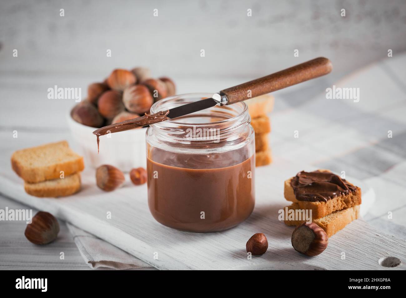 Petits toasts avec tartinade au chocolat noisette pour le petit déjeuner sur fond de bois blanc Banque D'Images