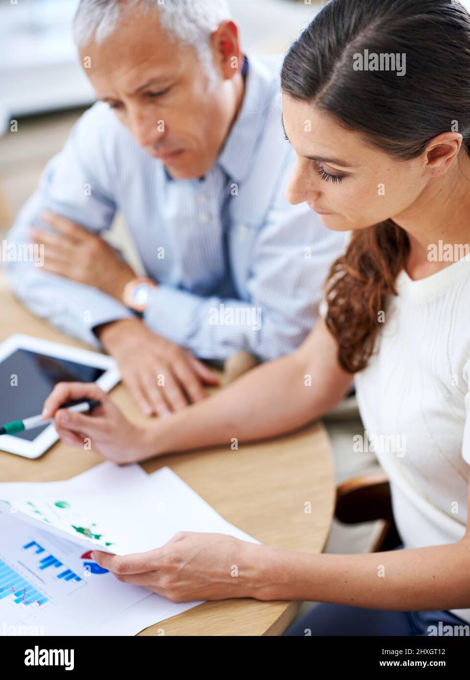 C'est dur et dur. Photo de deux collègues qui lisent des documents pendant qu'ils sont assis à un bureau dans un bureau. Banque D'Images