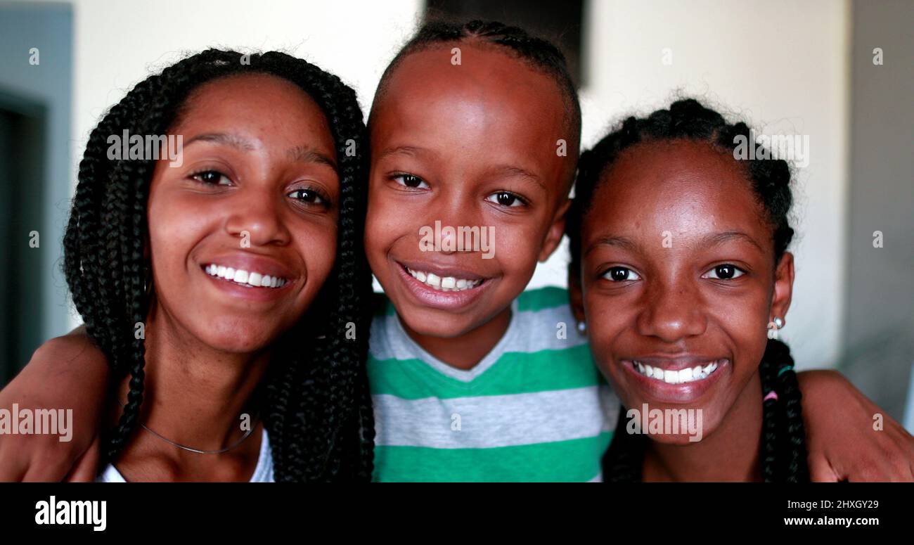 Petit frère embrassant les sœurs adolescentes. Les enfants africains de race mixte d'origine ethnique noire Banque D'Images