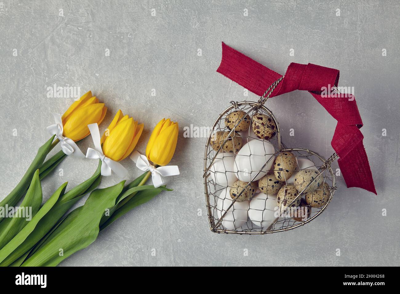 Œufs de poulet et de caille dans un panier métallique tissé en forme de coeur Banque D'Images