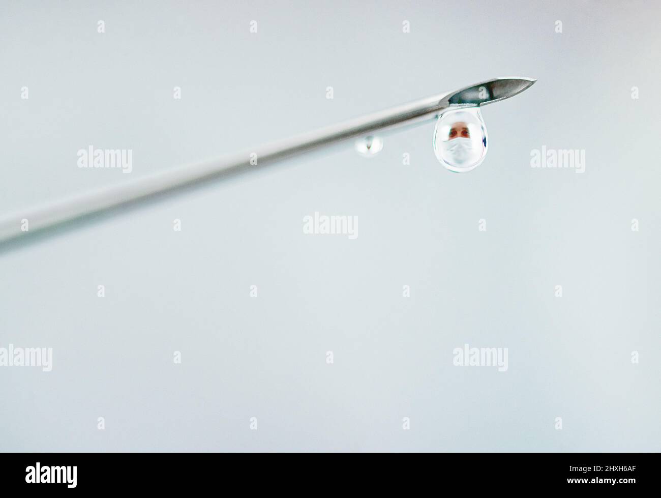 Le visage derrière une percée clinique. Injection d'une aiguille chirurgicale dont le médicament s'égoutte. Banque D'Images