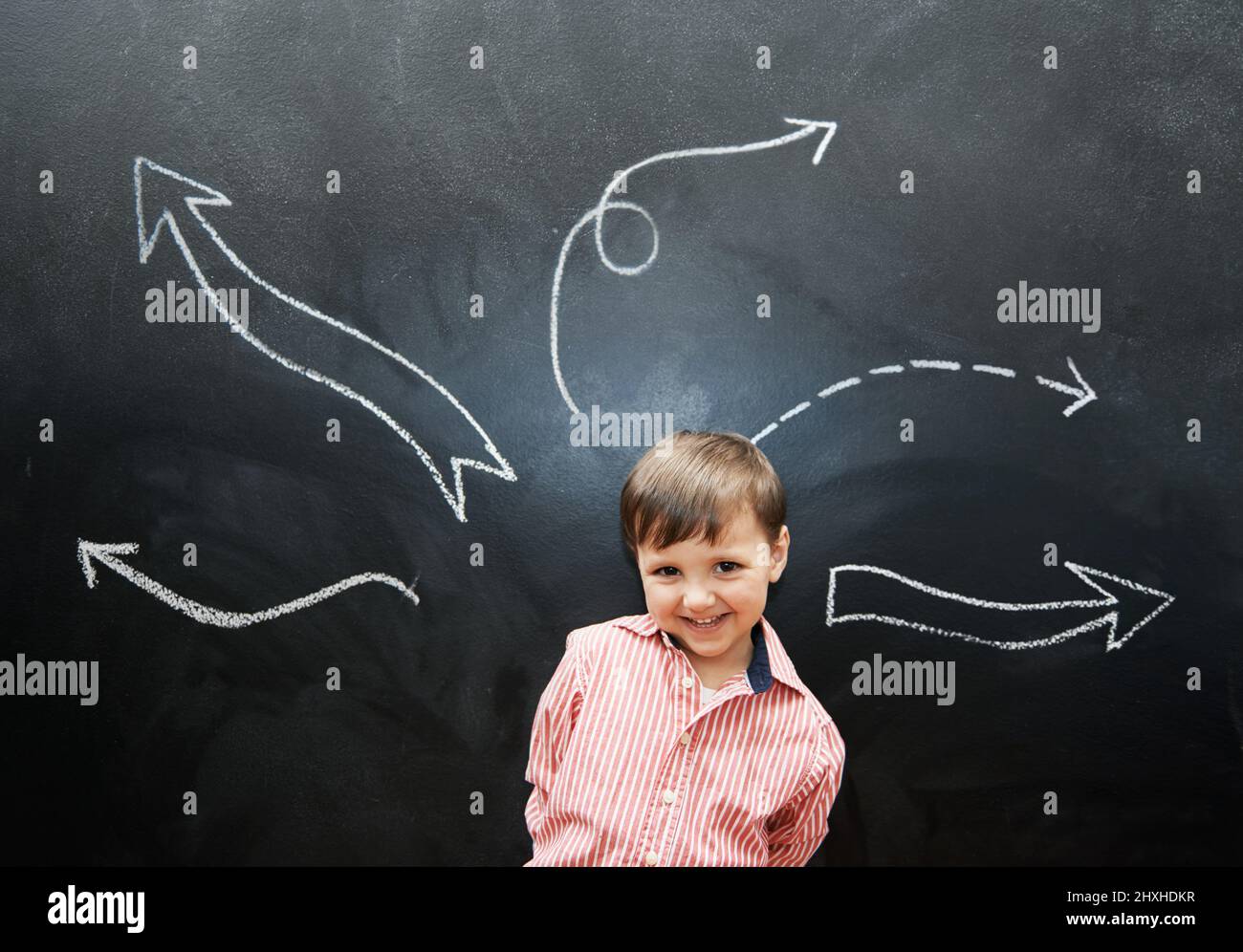 Le dessin est tellement amusant. Photo studio d'un adorable petit garçon avec dessins à la craie derrière lui. Banque D'Images