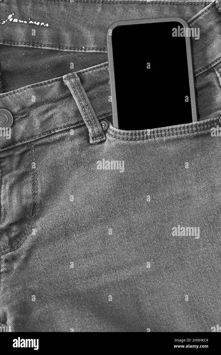 Partie supérieure d'un Jean noir ancien et d'un smartphone avec écran noir Banque D'Images