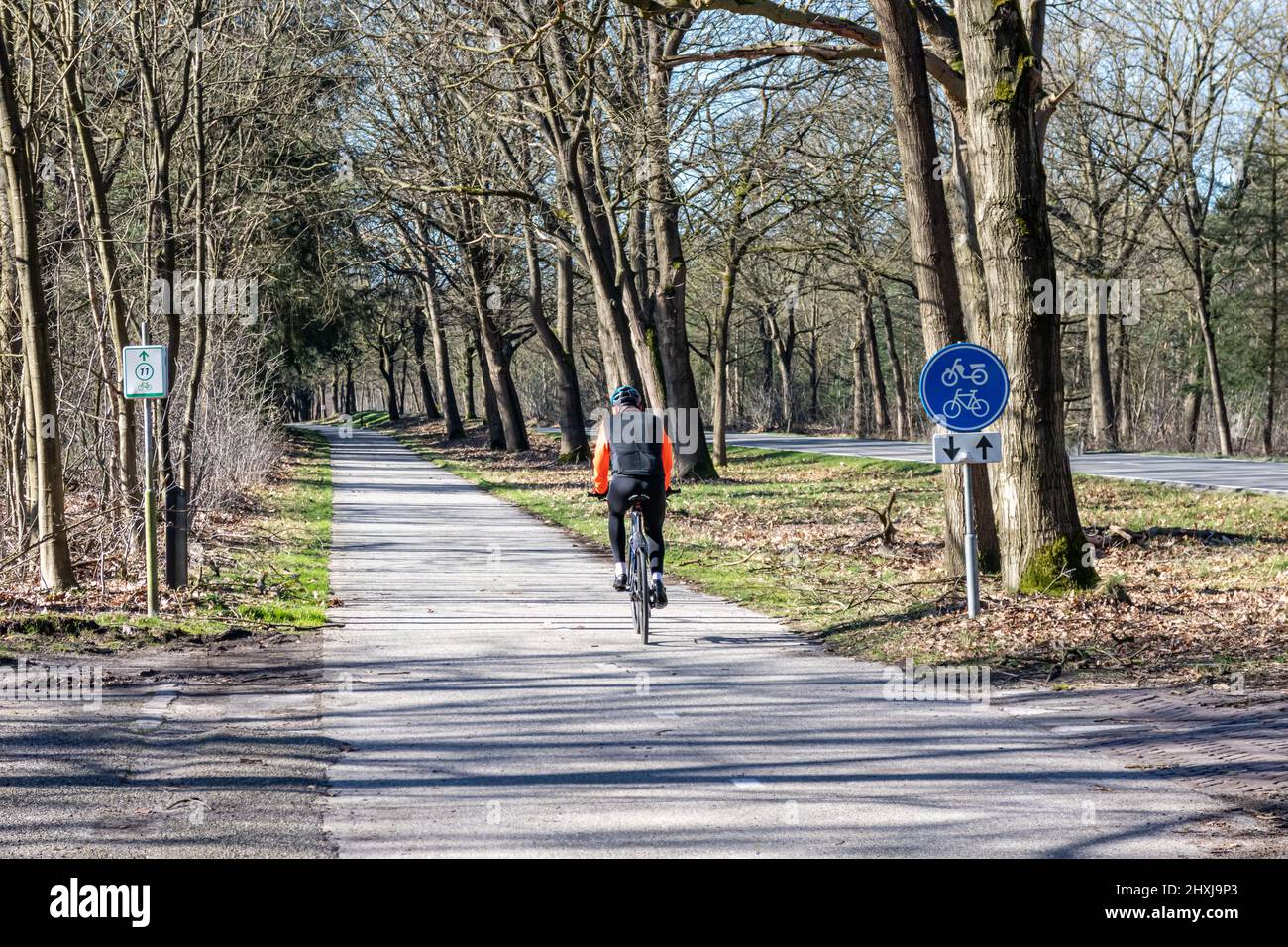 Someren, Brabant Nord, pays-Bas. 27 février 2022. Cycliste pédalant sur une piste cyclable, une route de campagne, panneau indiquant: Piste cyclable et mobylette, rou Banque D'Images