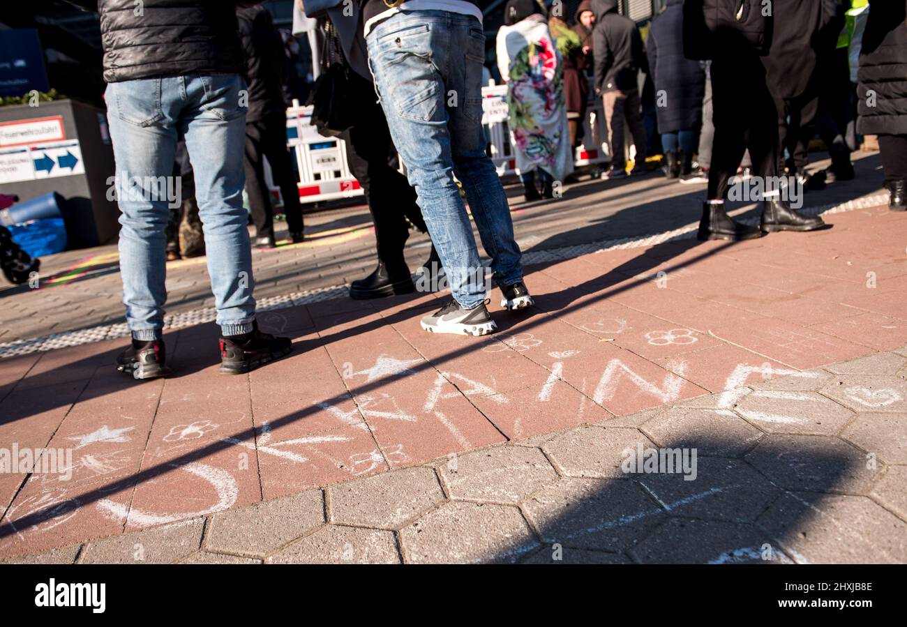 Hambourg, Allemagne. 13th mars 2022. Les réfugiés ukrainiens se trouvent devant le Bureau des migrations, au point d'enregistrement des réfugiés de Hammer Street. Ukraine » est écrit en craie sur le terrain. Credit: Daniel Bockwoldt/dpa/Alay Live News Banque D'Images