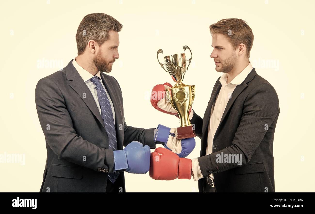 deux hommes d'affaires en gants de boxe tiennent la coupe du champion après la bataille pour le leadership, l'adversaire gagnant. Banque D'Images