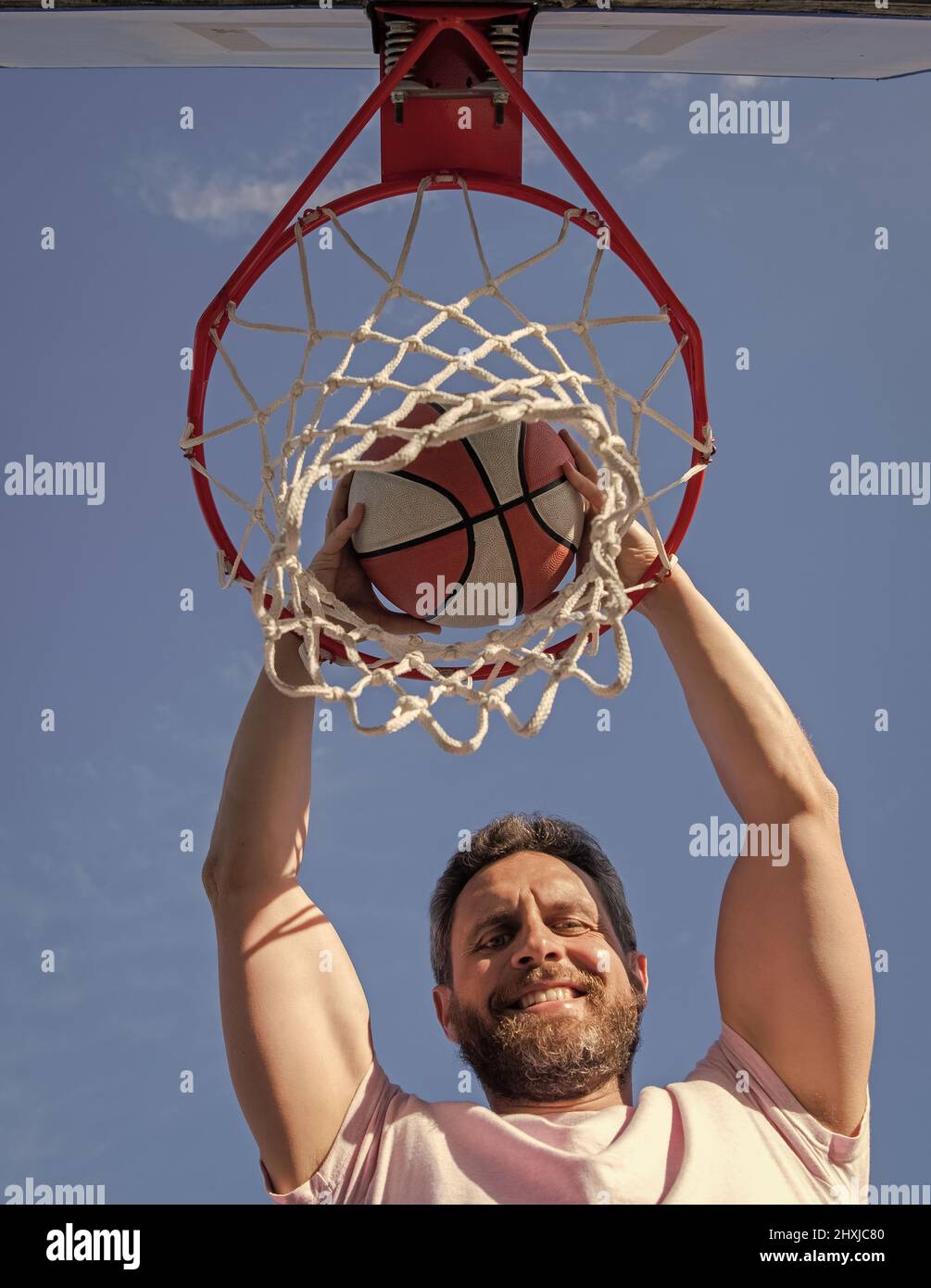 joyeux joueur de l'homme lancer le ballon de basket-ball dans le panier, gagnant Banque D'Images