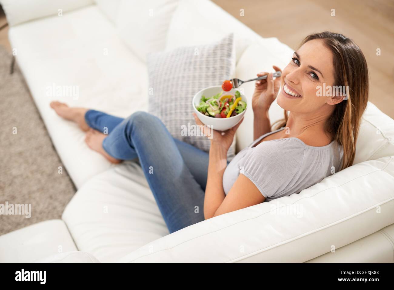 Ce n'est pas un régime qu'on appelle une saine alimentation. Une jeune femme appréciant sa salade avec un sourire. Banque D'Images