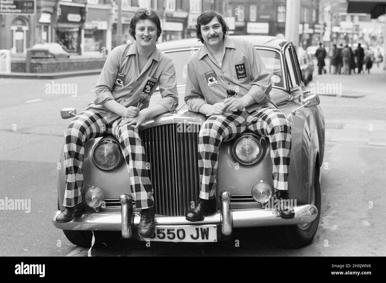Eric Bristow, un dard de dix-neuf ans, pose à Londres, assis au-dessus d'une Rolls Royce à côté du champion du monde actuel Alan Glazier. 6th mars 1977. Banque D'Images
