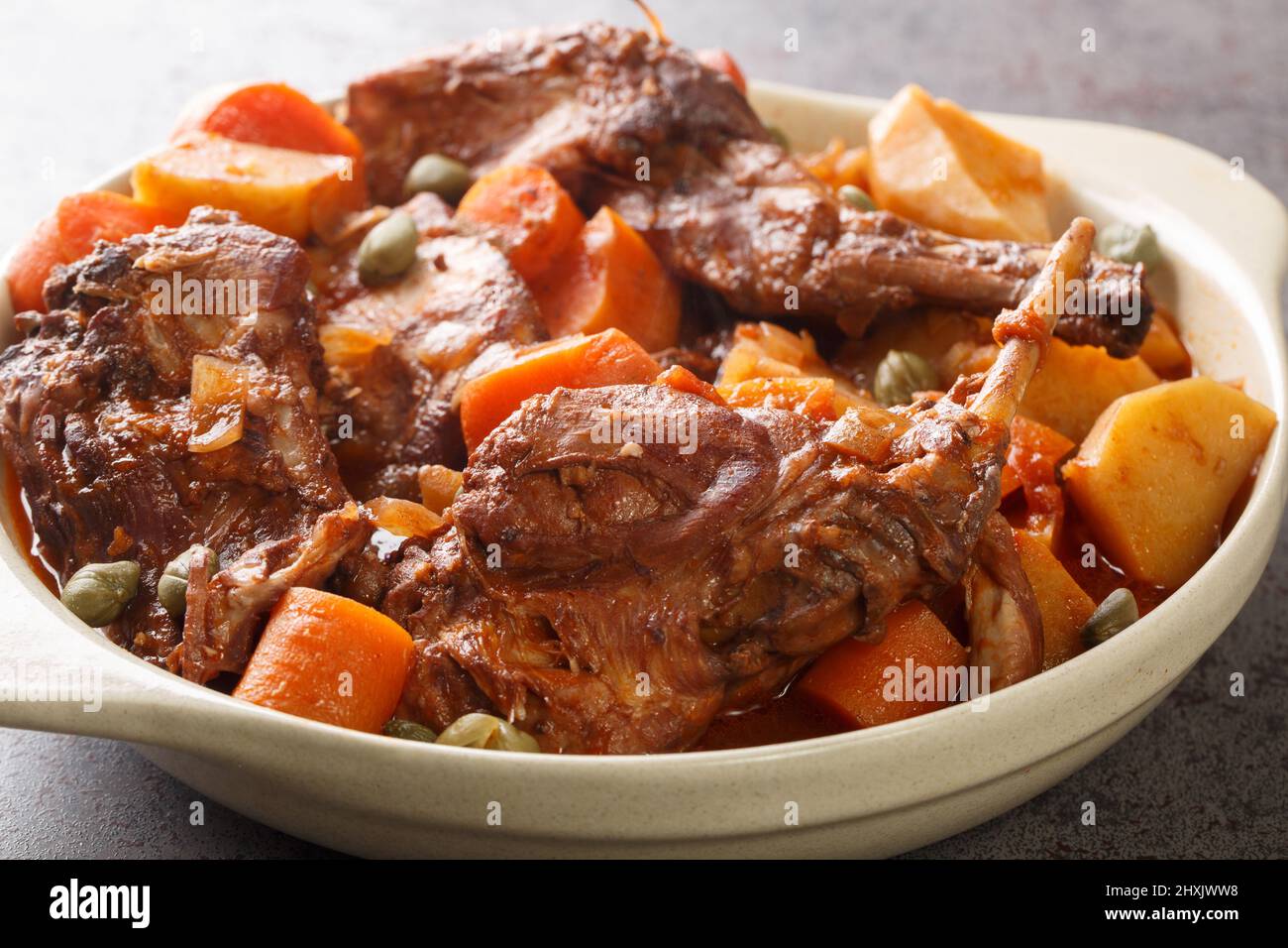 Lapin cuit au vin rouge avec légumes et ail dans une casserole sur la table. Horizontal Banque D'Images