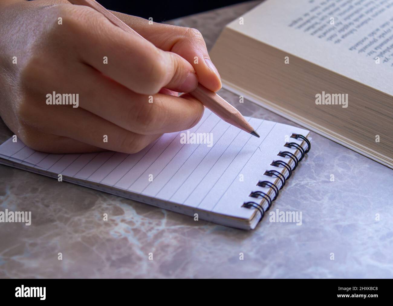 Gros plan photo de la main de femme prenant des notes sur la page de bloc-notes. Banque D'Images