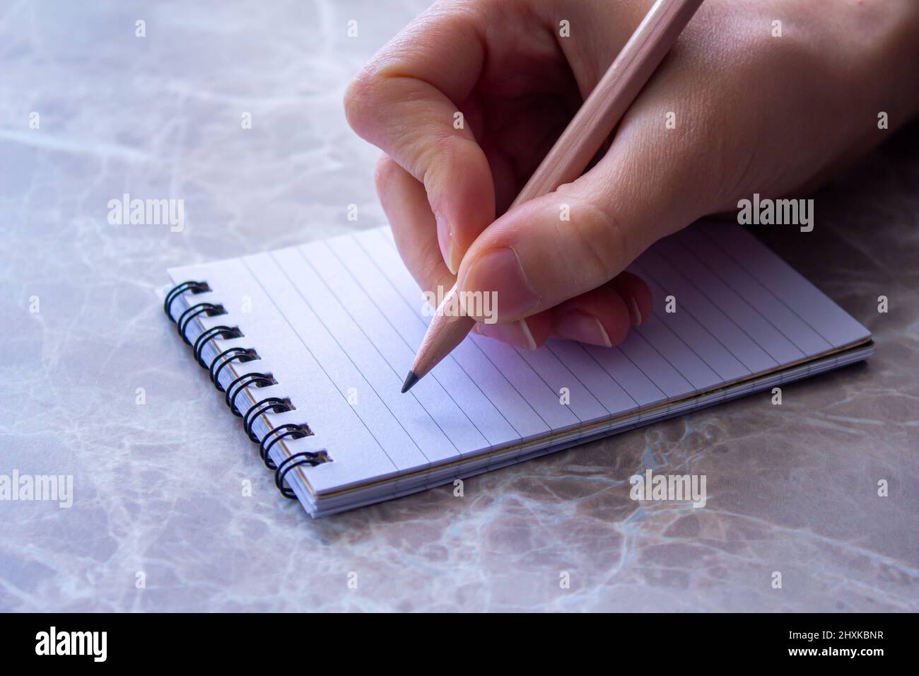 Gros plan photo de la main de femme prenant des notes sur la page de bloc-notes. Banque D'Images