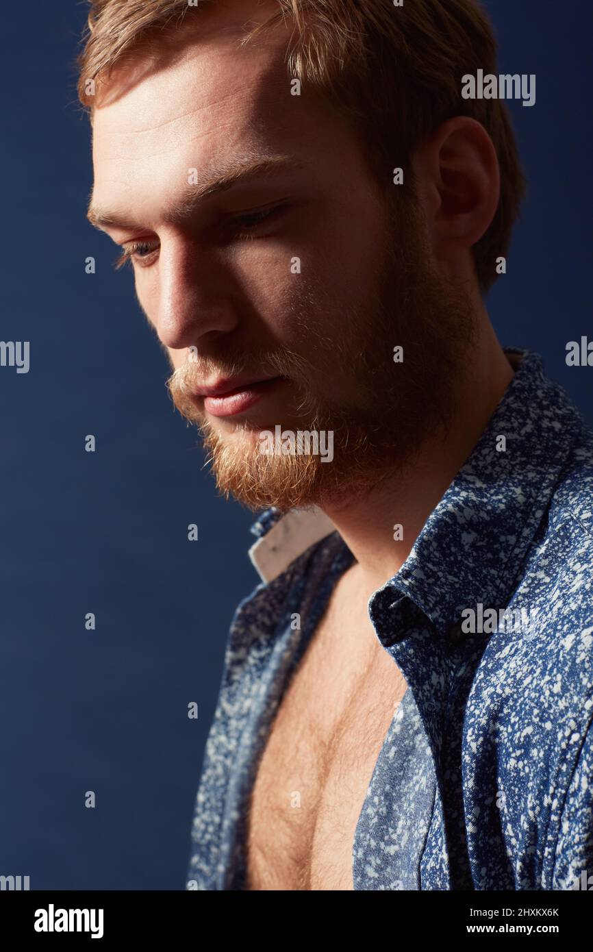 Profil d'un homme. Un jeune homme musclé portant une chemise ouverte et regardant loin. Banque D'Images