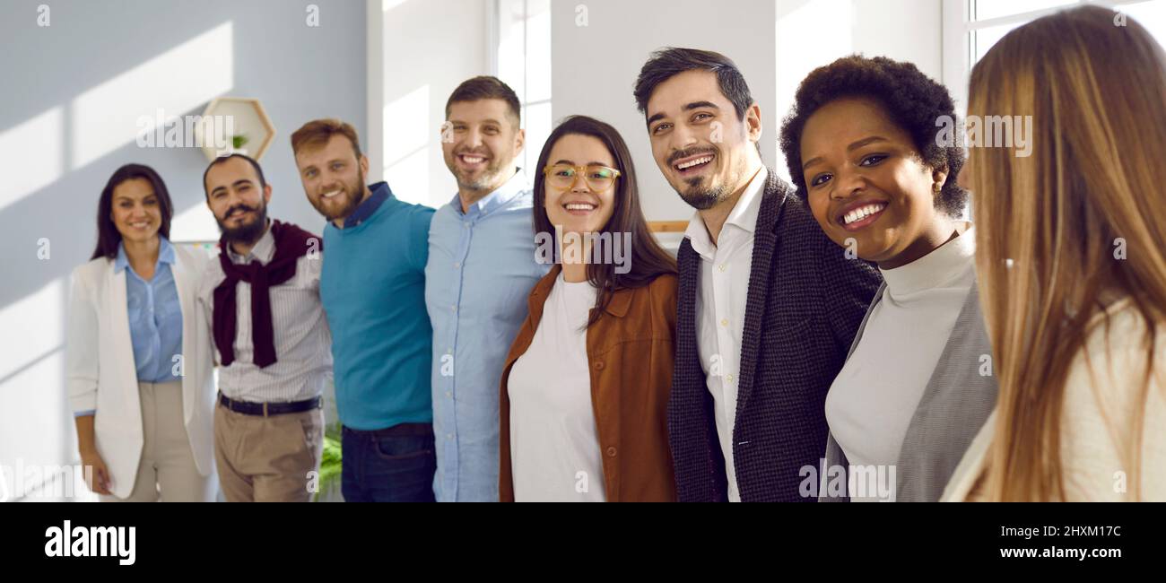 Une équipe multiraciale de jeunes gens d'affaires qui se serrent et sourient dans leur bureau Banque D'Images