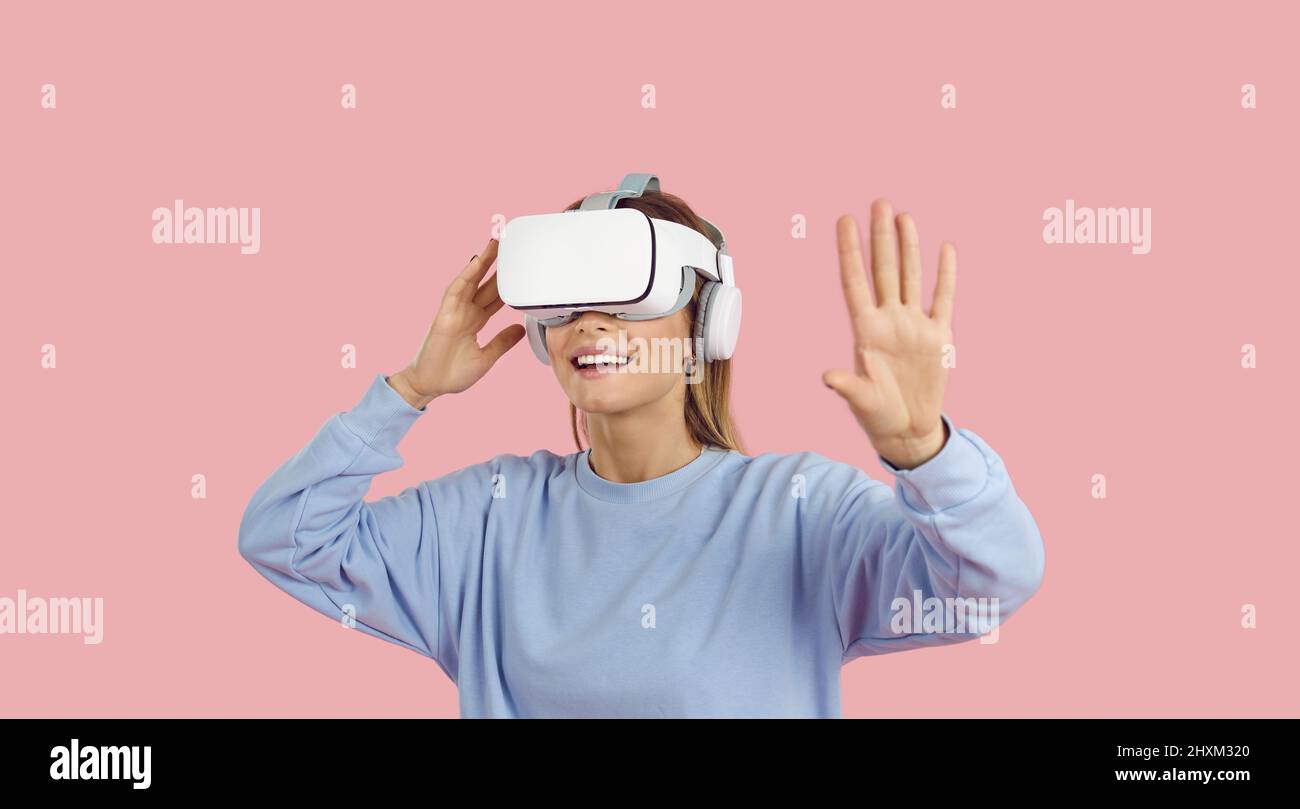 Jeune femme heureuse portant un micro-casque VR moderne, qui vit des mondes de la réalité virtuelle Banque D'Images
