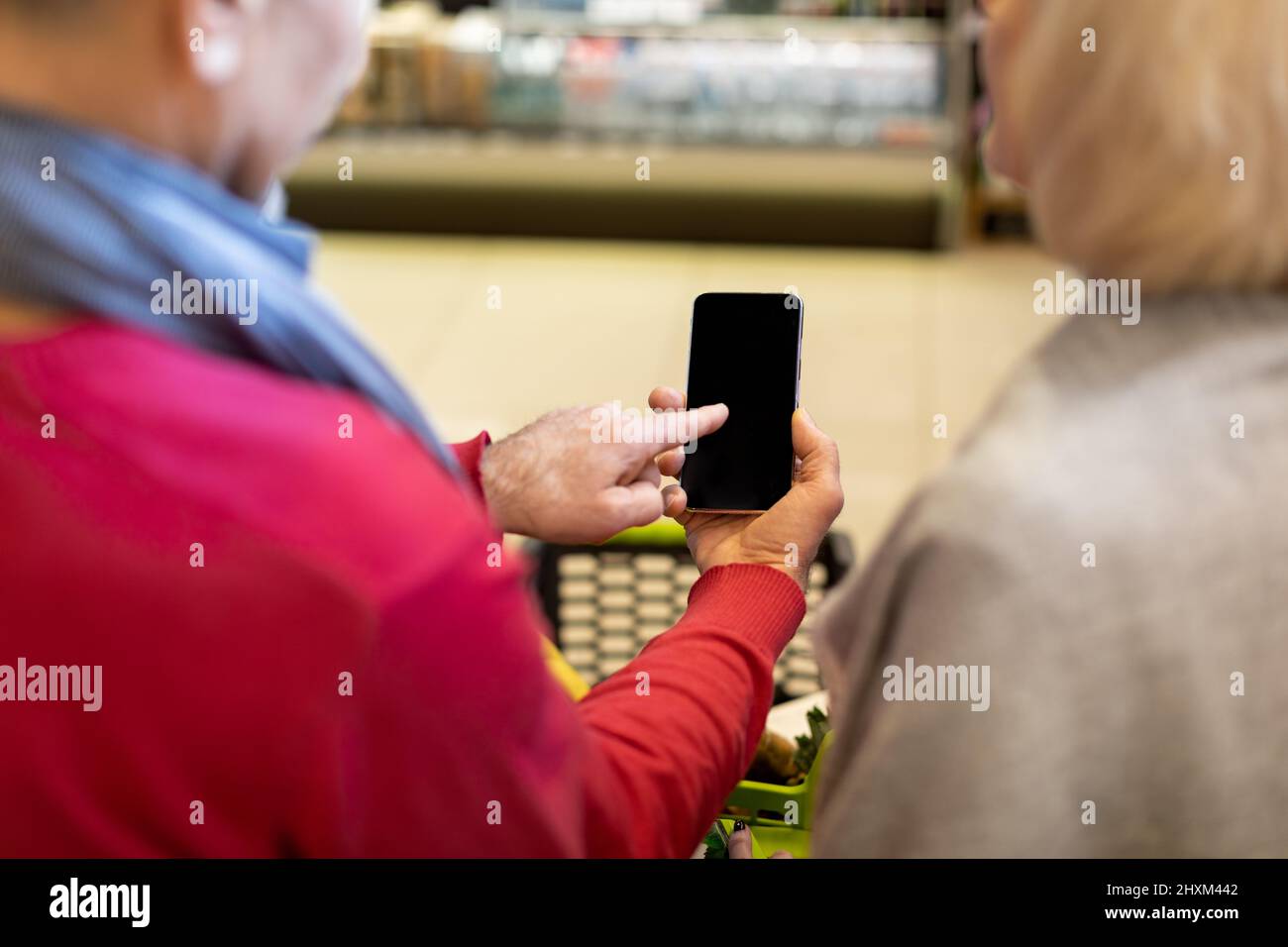 Couple senior méconnu utilisant un téléphone intelligent lors de ses achats Banque D'Images