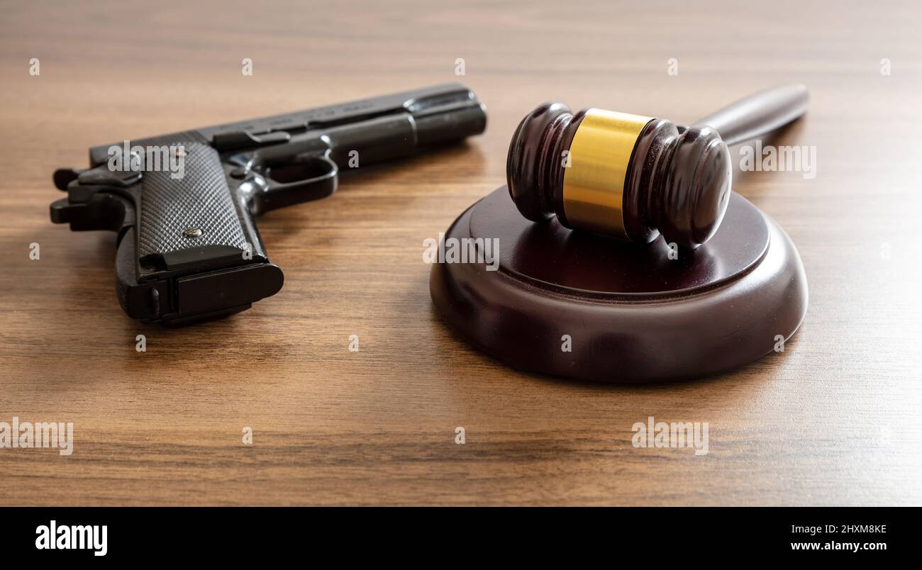 Crime, port d'armes à feu et utilisation de la punition concept. Juge le gavel et arme de poing au bureau de l'avocat. Table de palais de justice en bois, vue rapprochée Banque D'Images