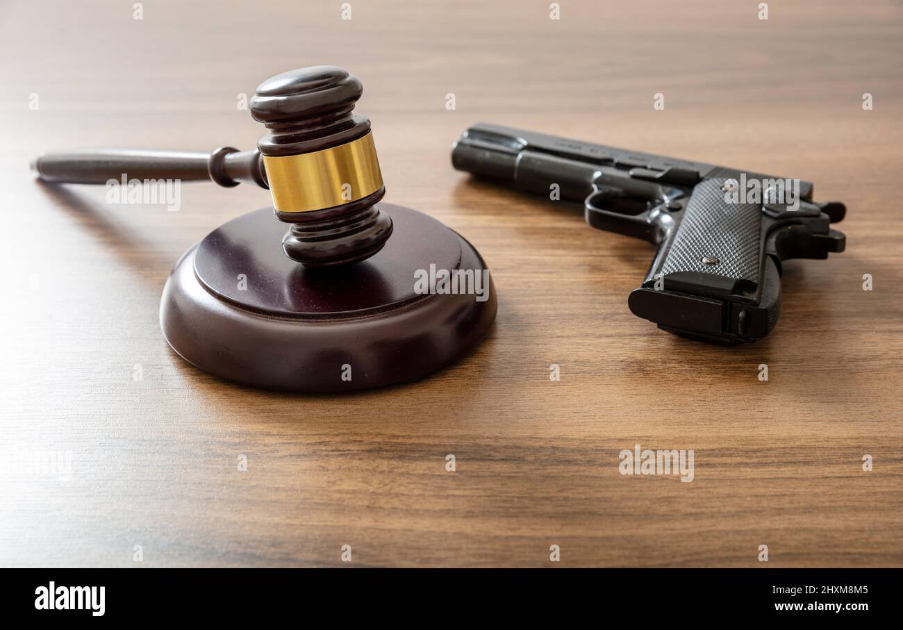 Juge le gavel et arme de poing au bureau de l'avocat. Crime, peine de meurtre concept. Table de palais de justice en bois, vue rapprochée Banque D'Images