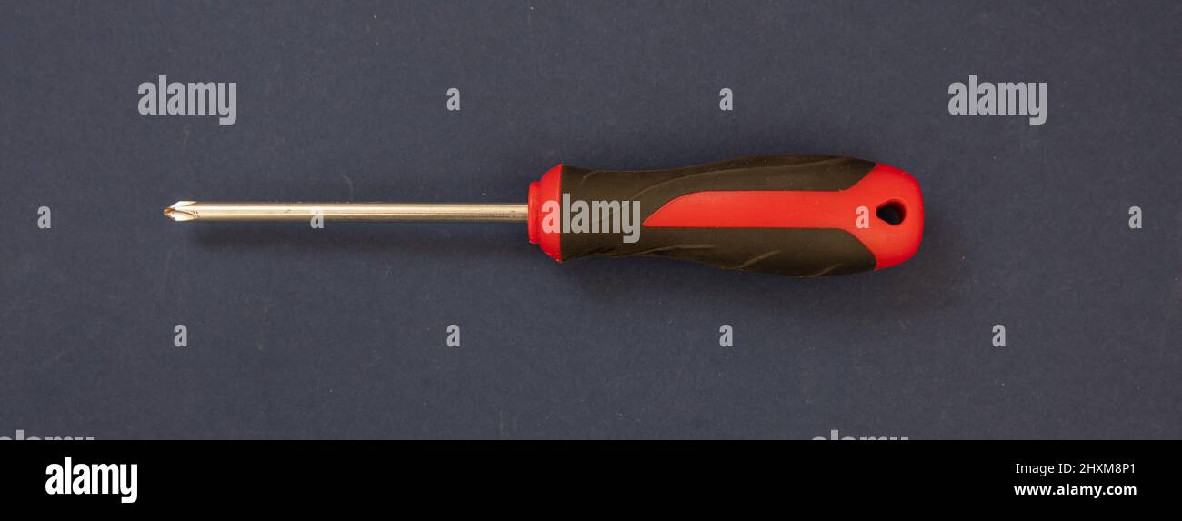 Tournevis cruciforme Phillips, rouge, manche en caoutchouc noir sur fond bleu. Outil à main, outil pour ingénieur, serrurier, électricien, carpen Banque D'Images
