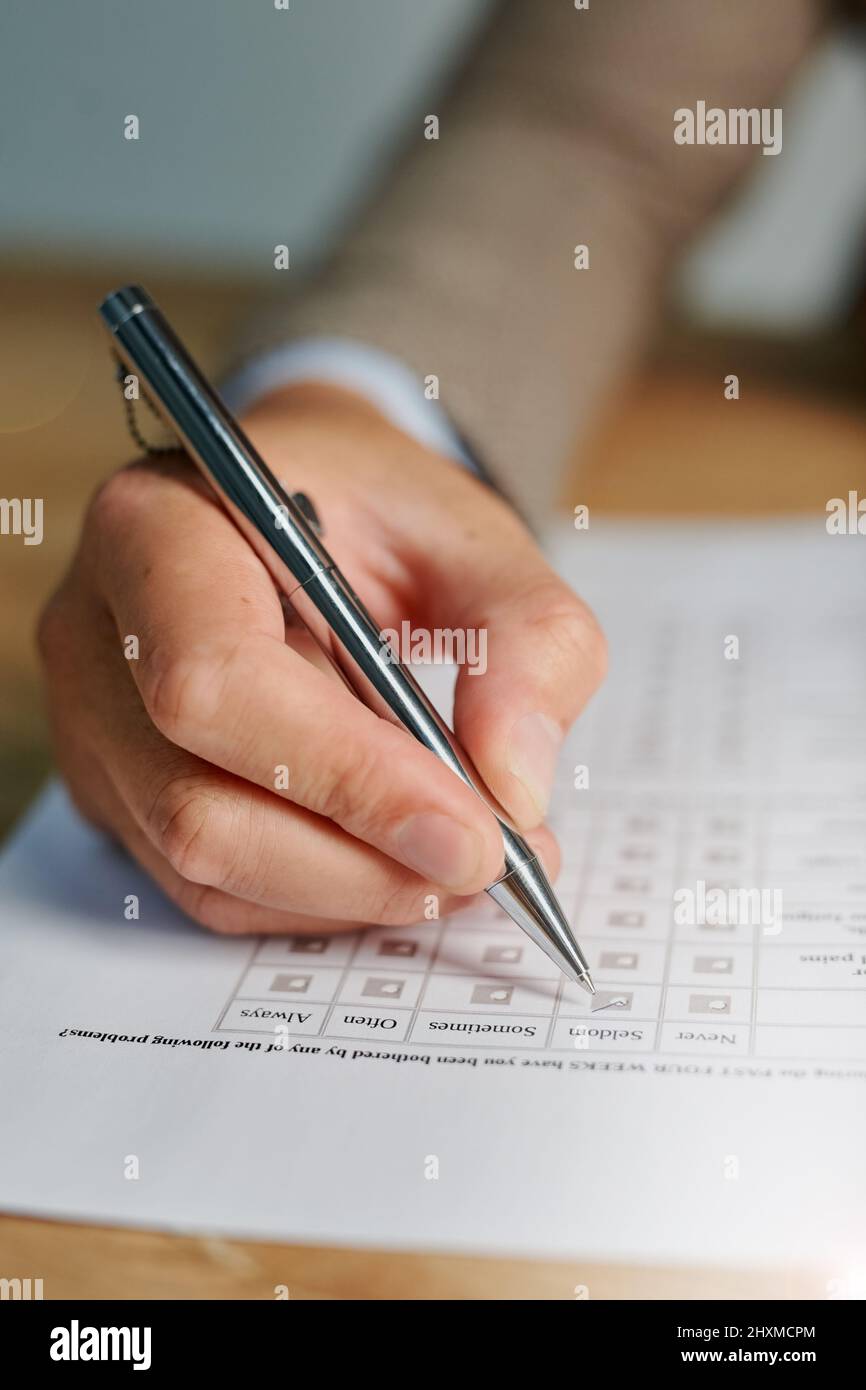 Cochez toutes les cases appropriées. Gros plan d'un homme remplissant un questionnaire médical. Banque D'Images