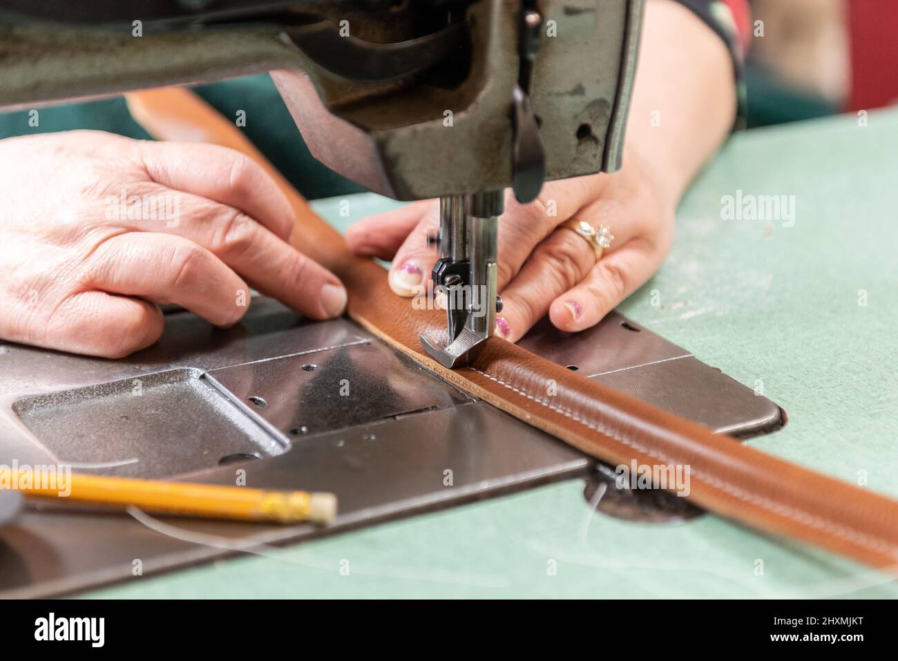 La poignée en cuir fait main est habilement guidée par les mains du travailleur de la production à l'usine. Banque D'Images