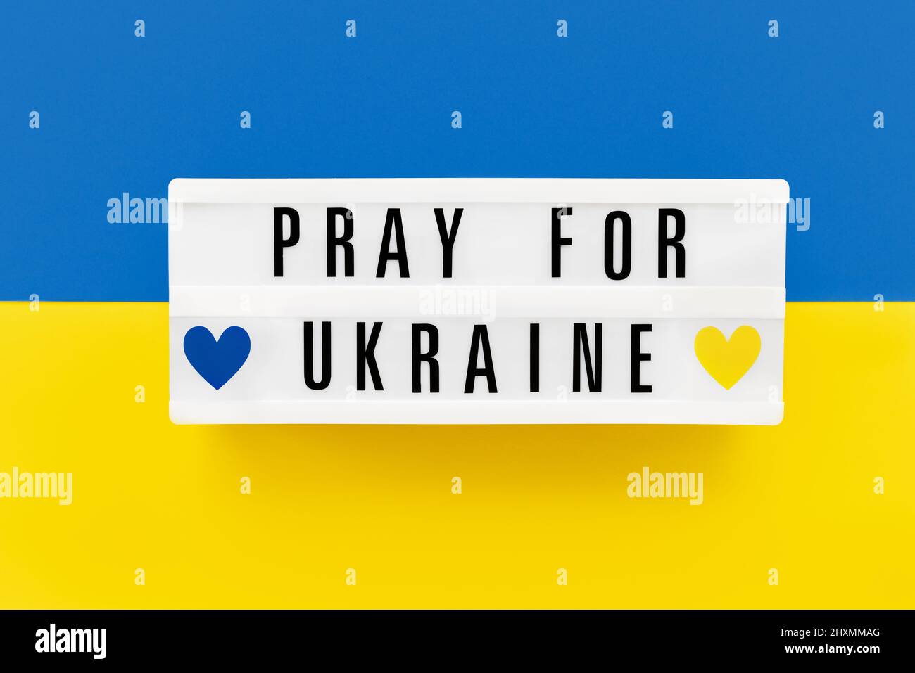 PRIEZ POUR L'UKRAINE écrit dans une visionneuse sur le drapeau ukrainien couleurs fond. Vue de dessus Banque D'Images