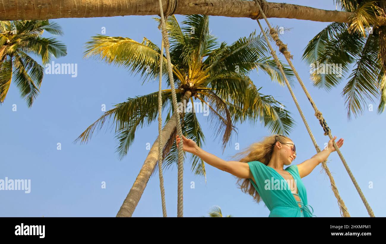 Jolie femme balançant sur une balançoire sur une plage tropicale, sur les rives de la mer turquoise. Concept voyage, promenades, repos dans la mer, tropical Resort côte détente voyage tourisme vacances d'été Banque D'Images