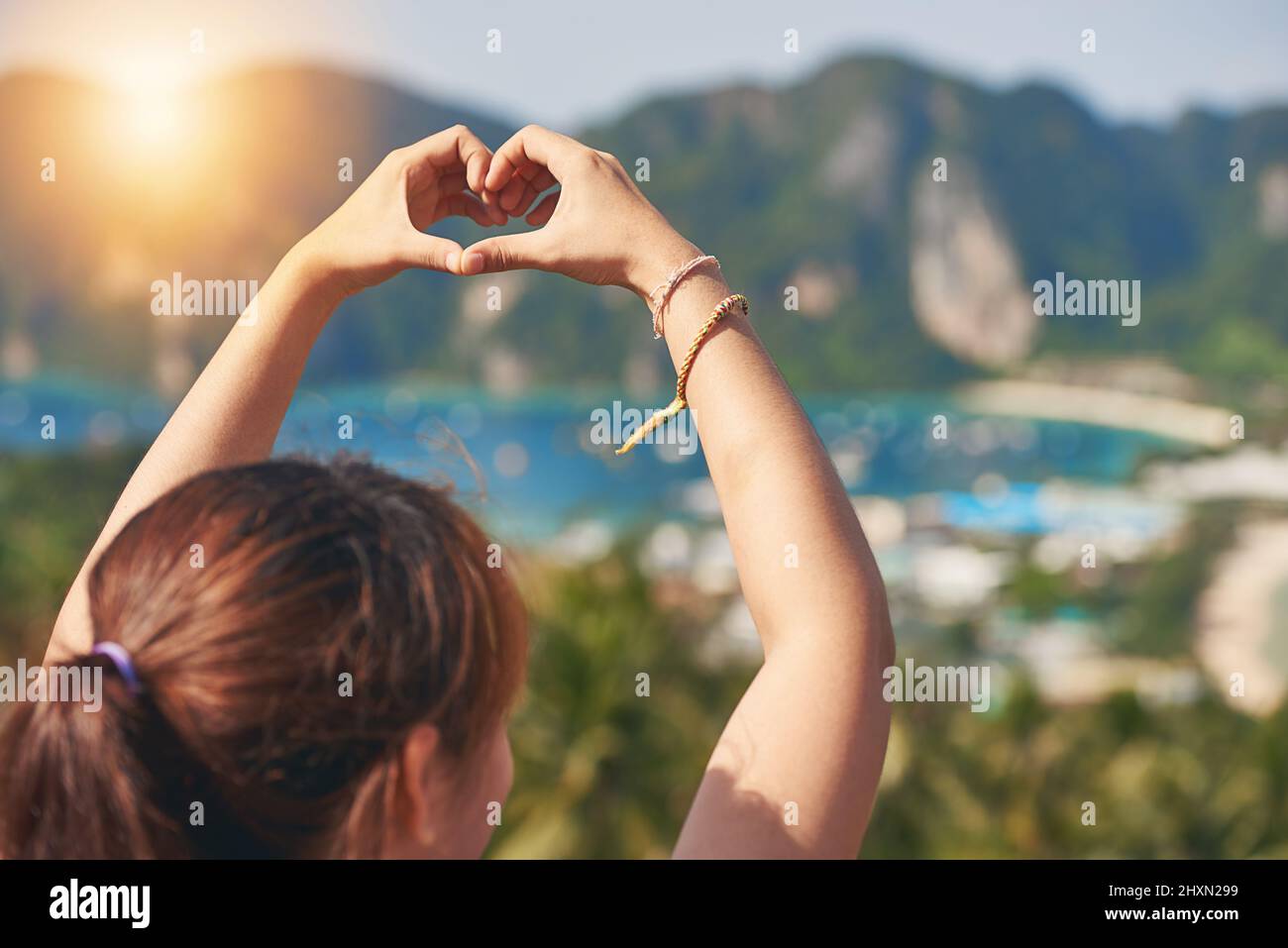 Cette île a volé son coeur. Photo d'un jeune touriste heureux faisant un coeur avec ses mains contre un beau paysage. Banque D'Images