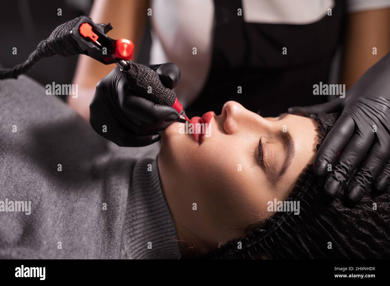 Portrait du maître pendant l'application de maquillage permanent sur les lèvres. Tatouage sur le visage et micropigmentation des lèvres. Professionnel Banque D'Images