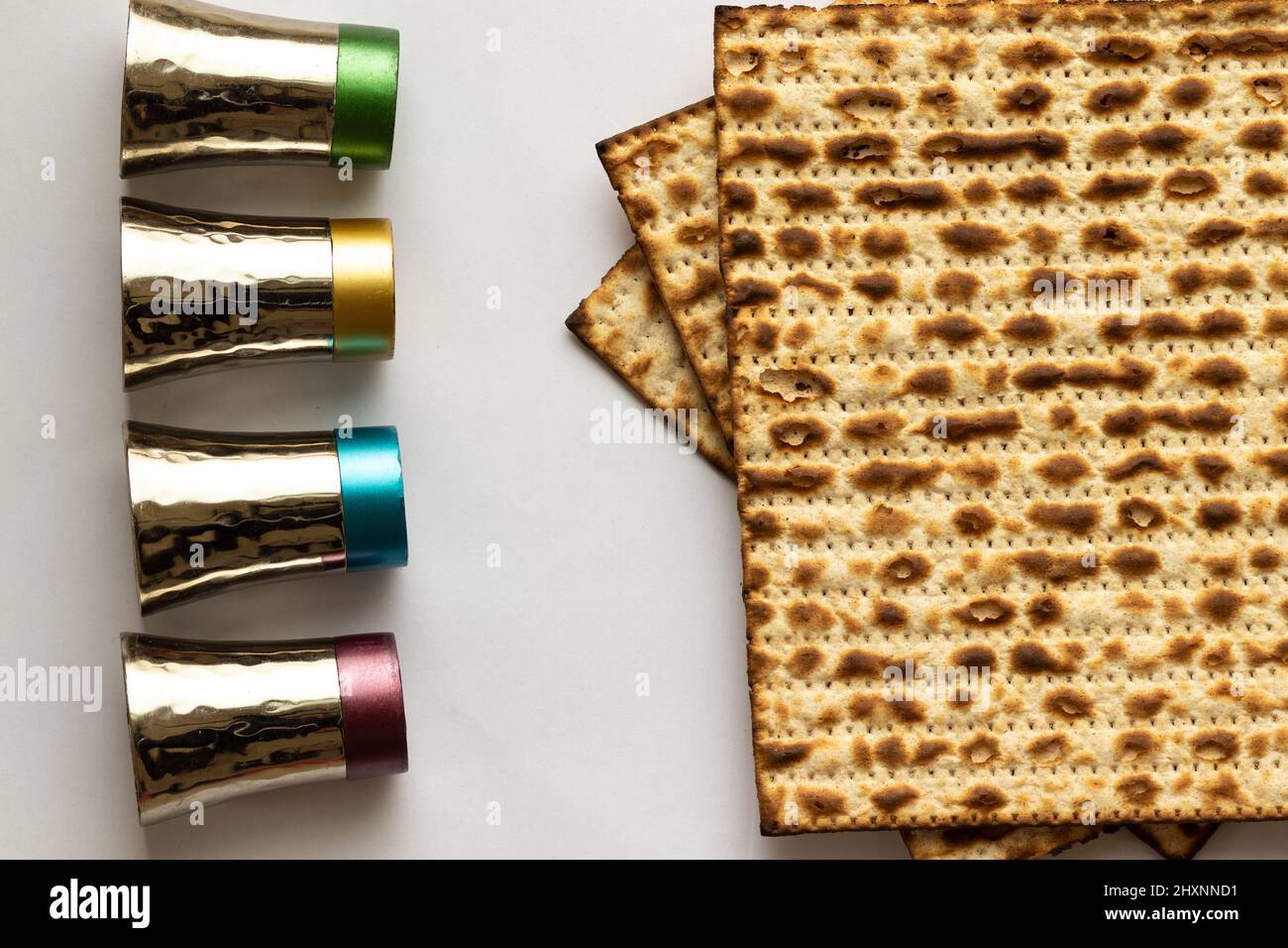Trois matzahs - pain juif pour la Pâque. À côté de quatre petites tasses argentées. Arrière-plan blanc Banque D'Images