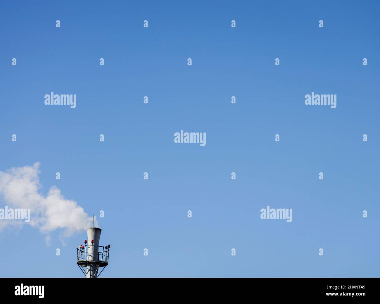 la cheminée industrielle émet des panaches de fumée et de pollution dans un ciel bleu clair et clair Banque D'Images