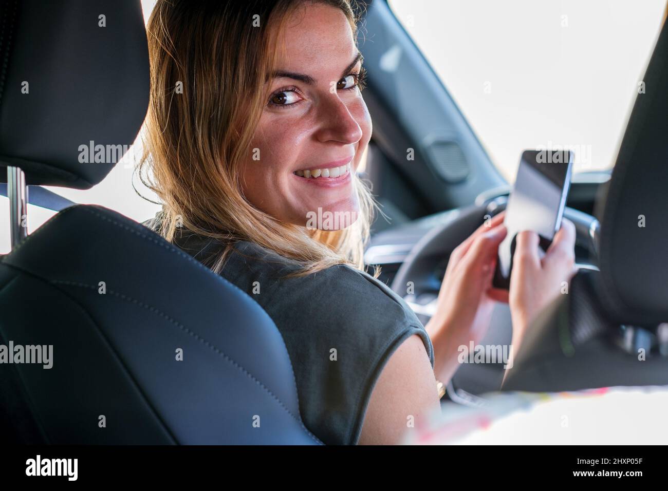 Femme qui a configuré son téléphone intelligent avec sa voiture Banque D'Images