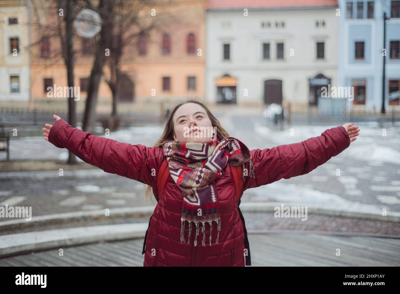 Jeune femme heureuse avec le syndrome de Down avec les bras ouverts en ville en hiver Banque D'Images