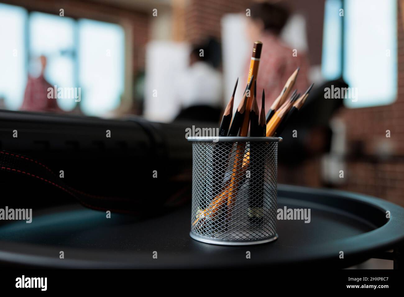 Gros plan des crayons graphiques debout sur la table dans le studio de l'école de créativité. En arrière-plan, diverses équipes dessinant des croquis de vase sur toile travaillant à la technique d'esquisse. Résolutions du nouvel an Banque D'Images