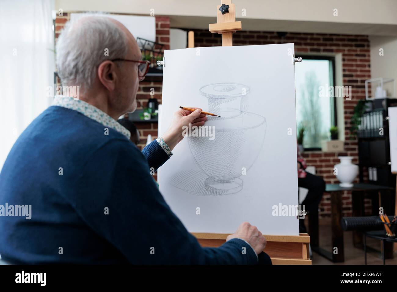 Homme peintre senior dessin vase modèle sur toile de peinture utilisant la technique d'esquisse pendant la classe d'art dans studio de créativité. Équipe diversifiée participant à une leçon créative développant les compétences artistiques Banque D'Images