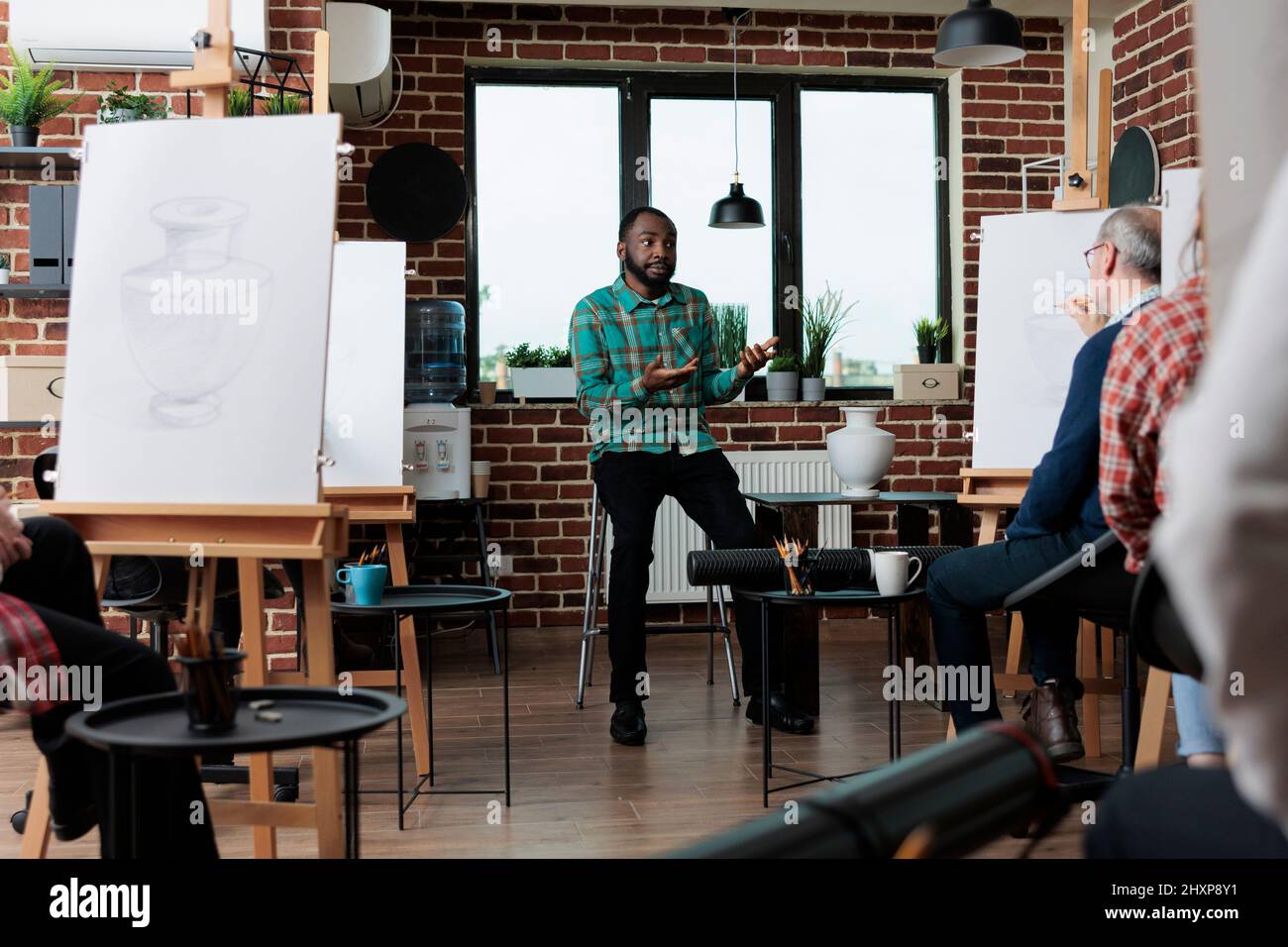 Professeur de peintre expliquant dessiner l'illustration aux étudiants en art, enseignant le processus d'esquisse ayant le modèle de vase pour l'inspiration. Groupe multiethnique de personnes créatives développant des compétences artistiques Banque D'Images