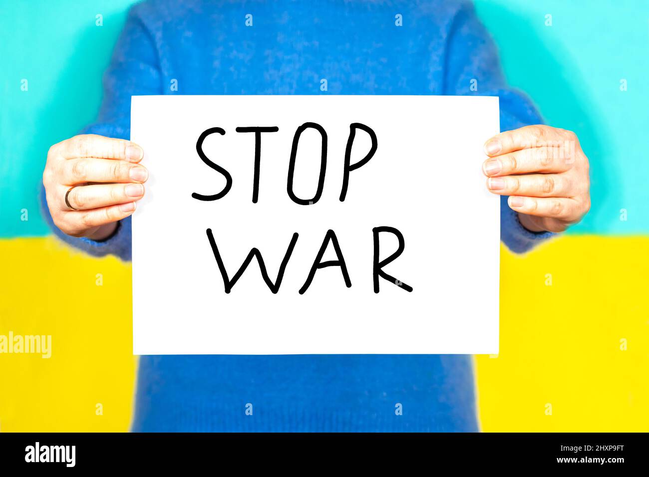 Une femme porte un foulard avec l'inscription Stop the war sur fond de drapeau ukrainien. Arrêter la guerre. Banque D'Images