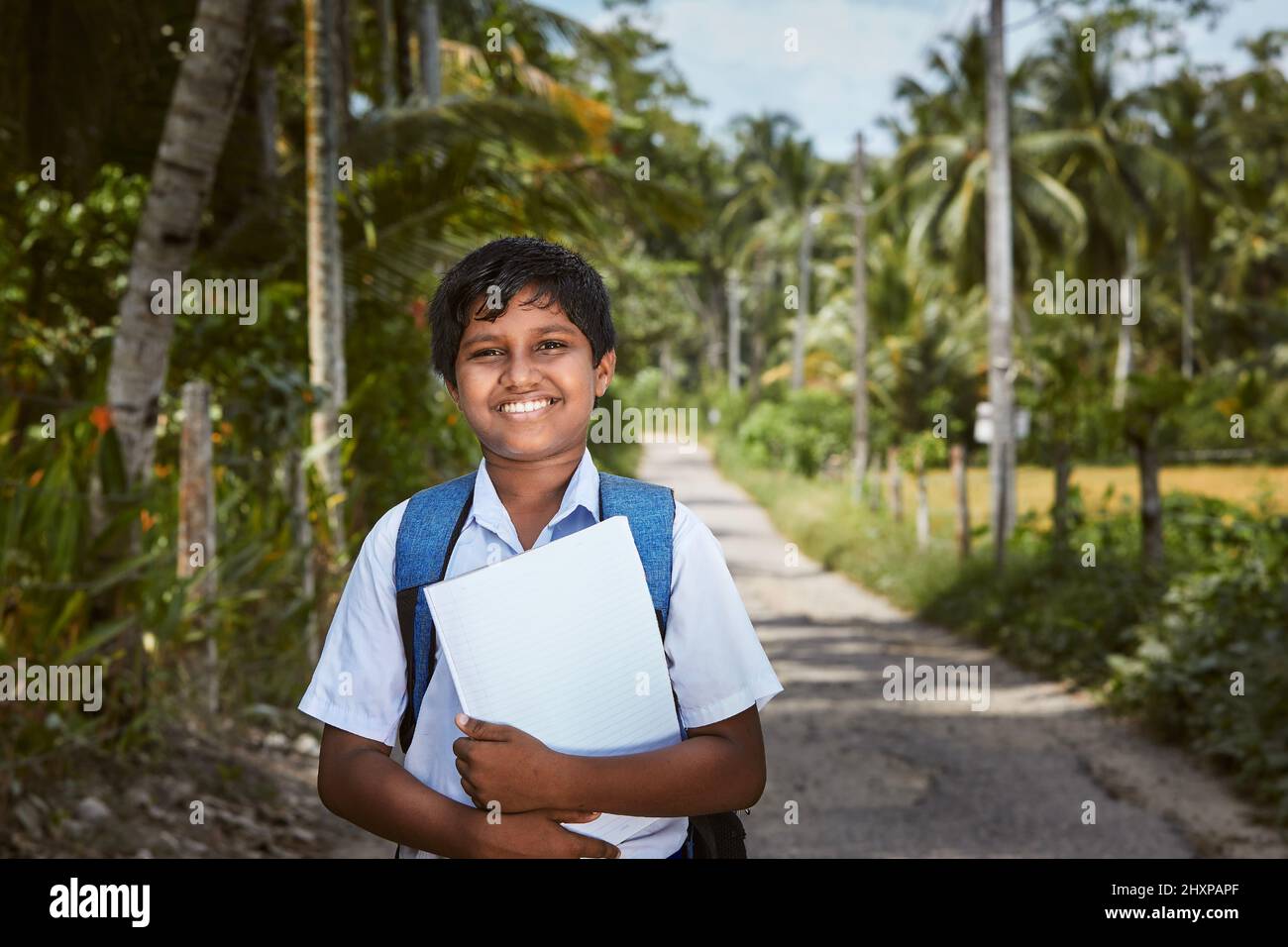 Un écolier en uniforme marche jusqu'à l'école. Portrait de garçon sur la route rurale au Sri Lanka. Banque D'Images