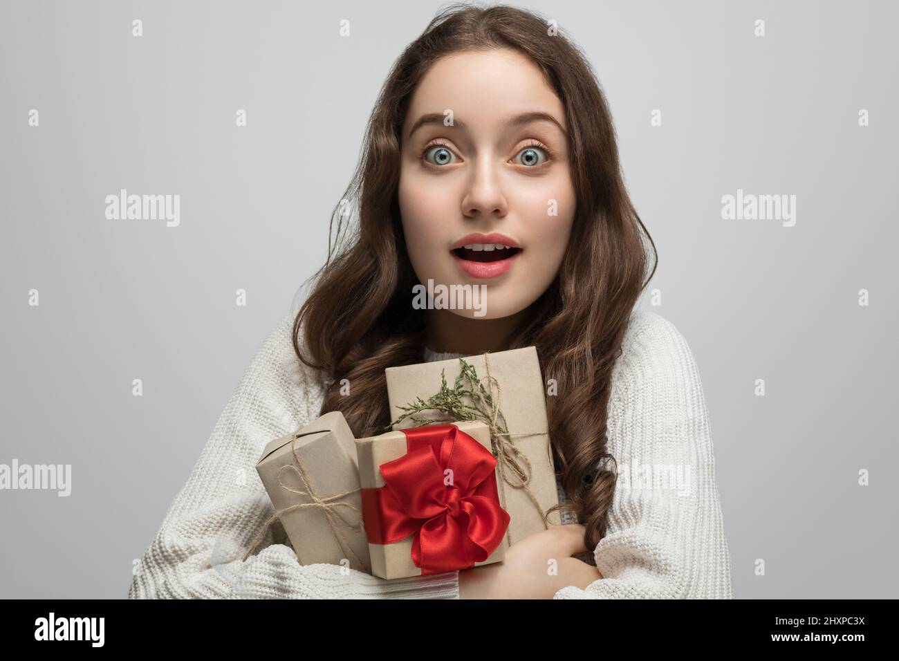 Une jeune fille avec de longs cheveux et un cadeau dans ses mains, regardant directement l'appareil photo Banque D'Images