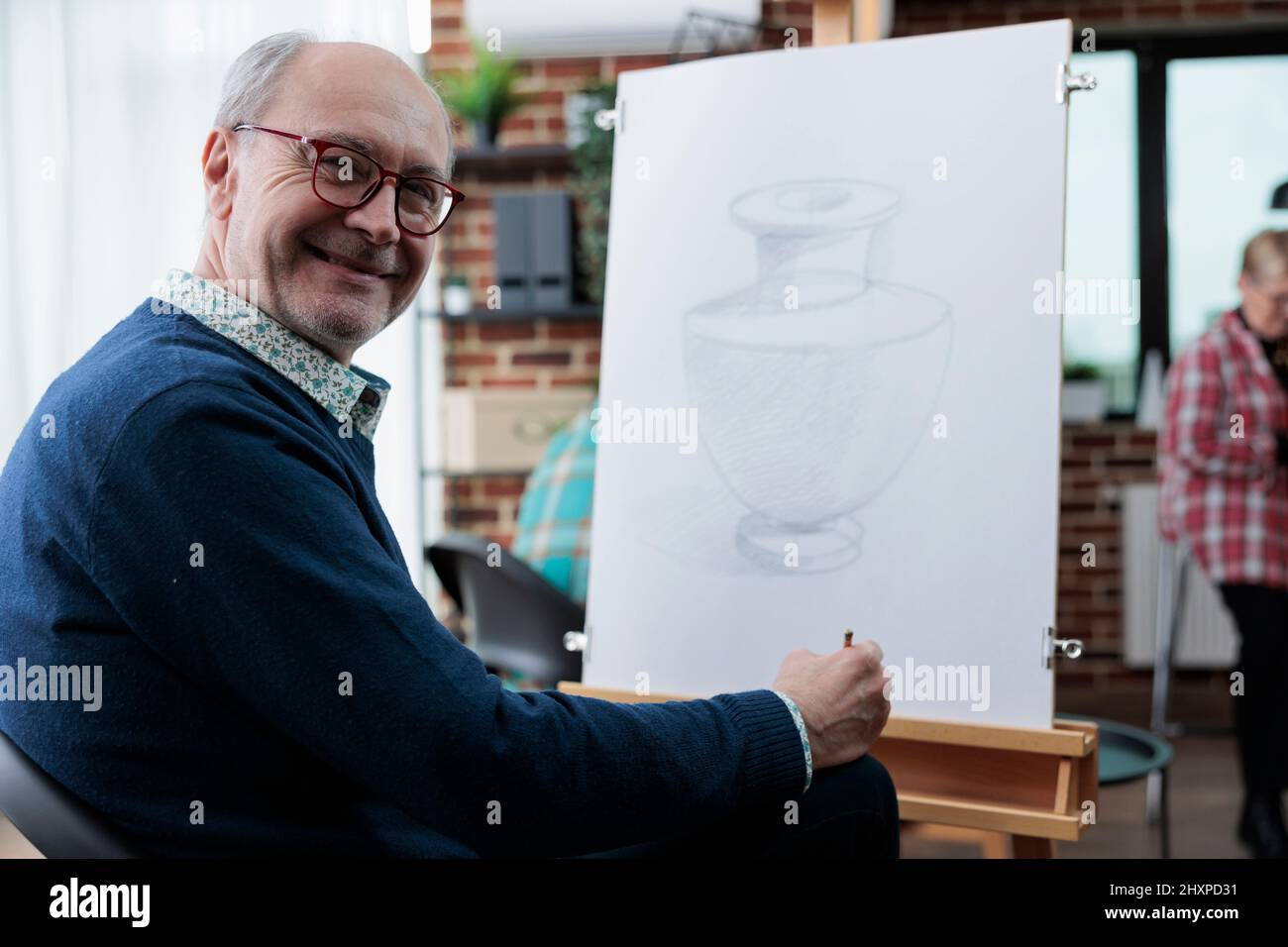 Portrait d'un artiste âgé souriant étudiant en train de dessiner un modèle de vase créatif à l'aide d'un crayon graphique travaillant à l'esquisse pendant la leçon d'art développant des compétences artistiques pour la croissance personnelle. Résolutions du nouvel an. Banque D'Images